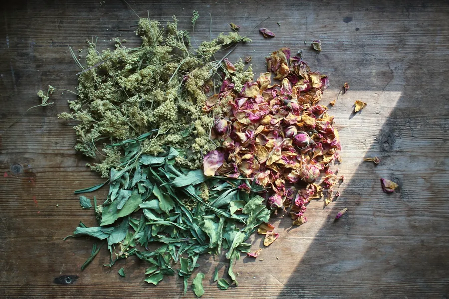 Plantes séchées et boutons de rose en tas sur une table en bois