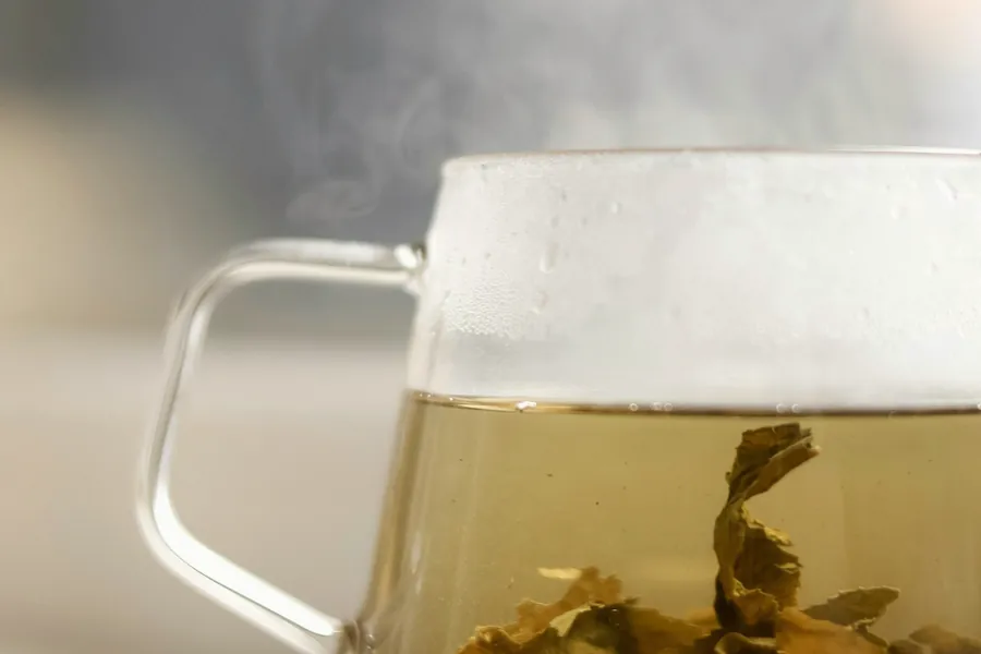 Infusion fumante dans une tasse en verre posée sur un rebord