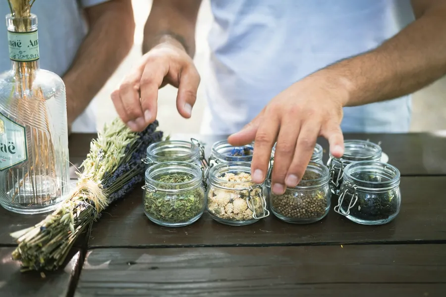 Mains remplissant de petits bocaux de plantes séchées près d'un bouquet de lavande